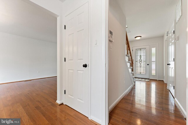 foyer entrance with wood finished floors, stairway, and baseboards
