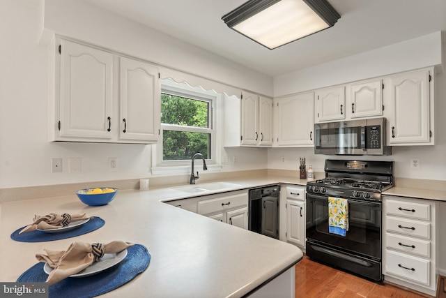 kitchen featuring black appliances, a sink, and white cabinetry