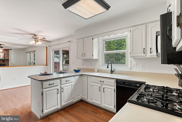 kitchen with a sink, black appliances, ceiling fan, a peninsula, and white cabinetry