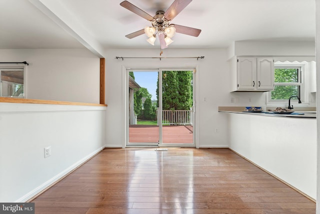 unfurnished dining area with plenty of natural light, light wood-type flooring, and a ceiling fan