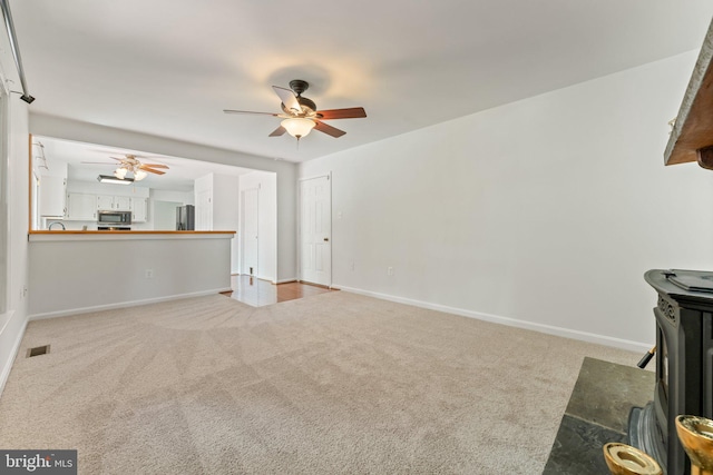 unfurnished living room featuring a ceiling fan, carpet floors, and baseboards