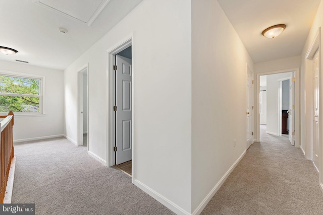 hallway with light colored carpet and baseboards