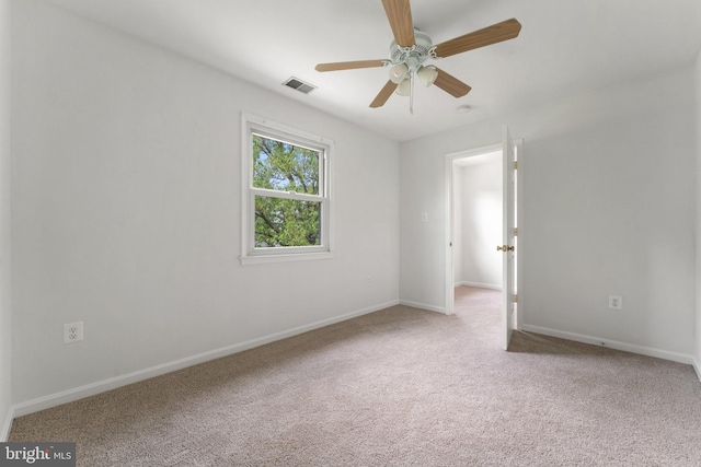 empty room with light carpet, a ceiling fan, and baseboards