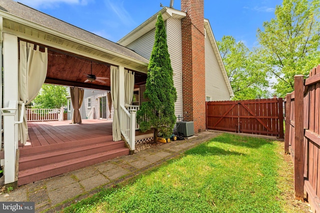 rear view of property with a ceiling fan, a chimney, a gate, a deck, and a shingled roof