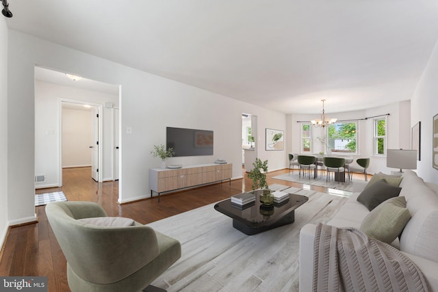 living area with a chandelier, plenty of natural light, and wood finished floors
