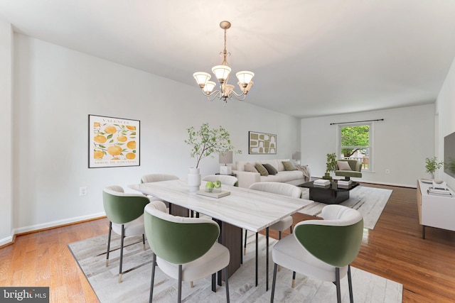 dining room with a chandelier, light wood finished floors, and baseboards