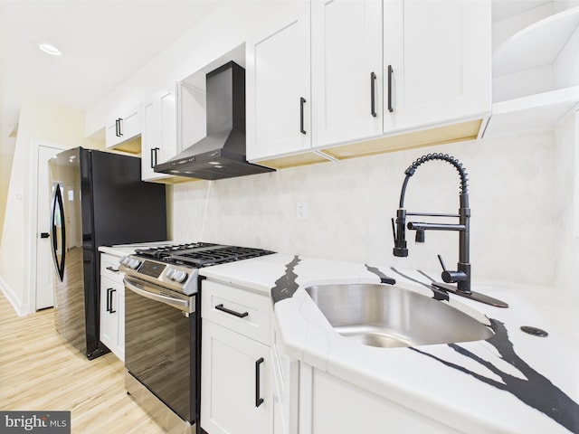 5135 N Fairhill St, Philadelphia, PA 19120 - kitchen with gas range, wall chimney range hood, a sink, light wood-type flooring, and white cabinetry