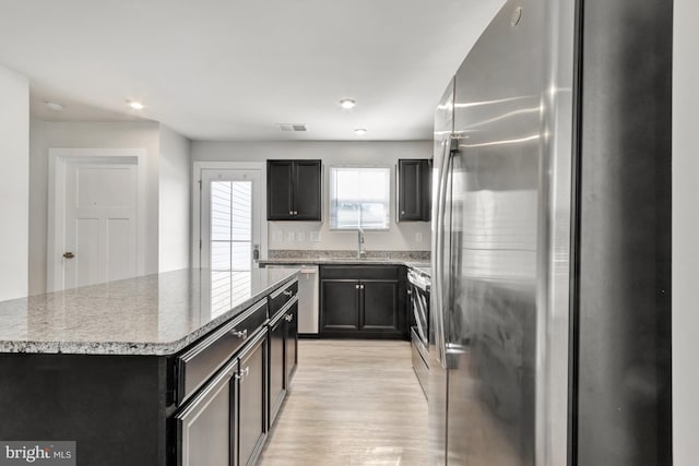 28010 Dew Drop Ln, Millville, DE 19967 - kitchen with appliances with stainless steel finishes, a sink, light wood finished floors, a kitchen island, and visible vents
