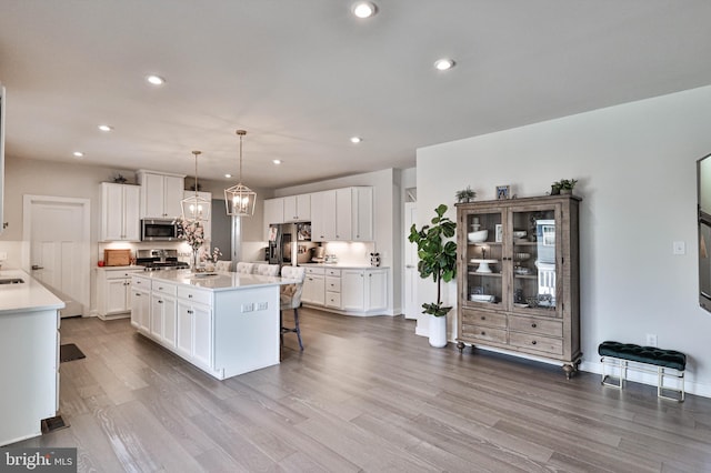 3911 Dewalt St, Bethlehem, PA 18020 - kitchen featuring stainless steel appliances, a kitchen breakfast bar, white cabinetry, and wood finished floors