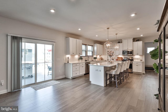 3911 Dewalt St, Bethlehem, PA 18020 - kitchen with wood finished floors, a kitchen bar, a center island, white cabinets, and stainless steel appliances