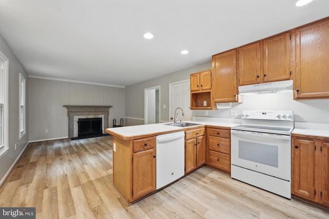 kitchen featuring white appliances, under cabinet range hood, a sink, a peninsula, and light wood-style flooring