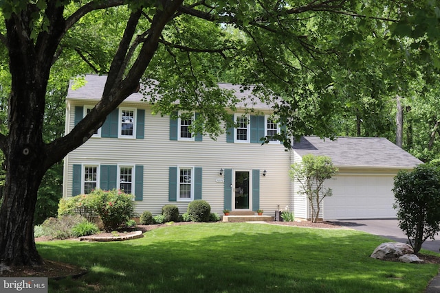 colonial house with an attached garage, a front lawn, and concrete driveway