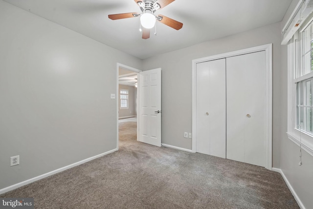 unfurnished bedroom with carpet, baseboards, a closet, and a ceiling fan