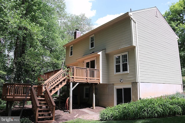back of house with stairs, a wooden deck, and a chimney