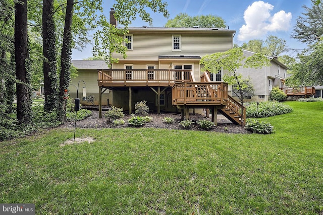 rear view of property with a deck, stairs, a chimney, and a lawn