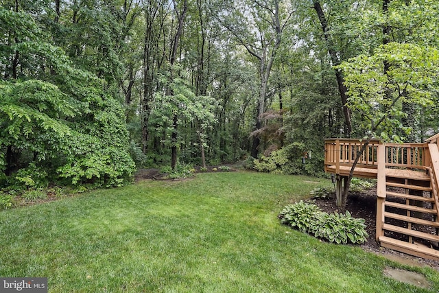 view of green lawn with a deck and stairway