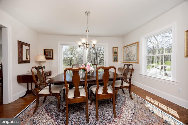 dining space featuring baseboards, a chandelier, and wood finished floors