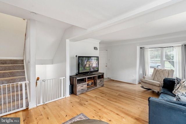 living room with light wood-type flooring, crown molding, and stairs