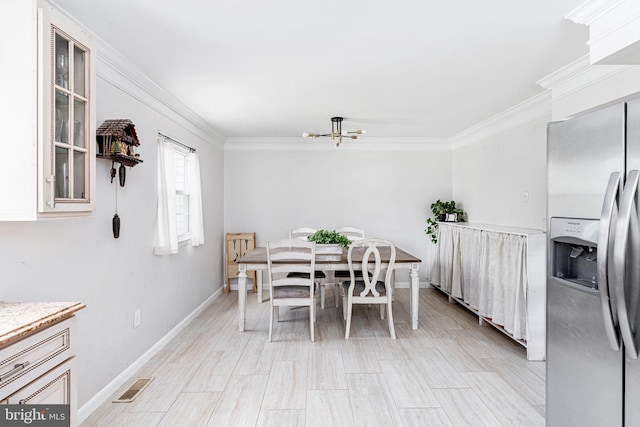dining space with crown molding, baseboards, and a chandelier