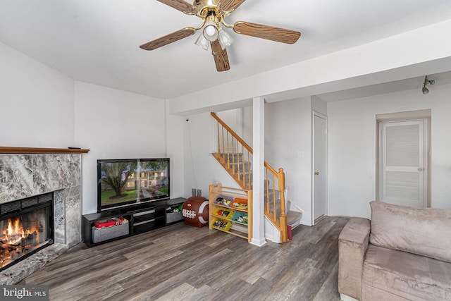 living room with wood finished floors, stairs, a premium fireplace, and a ceiling fan