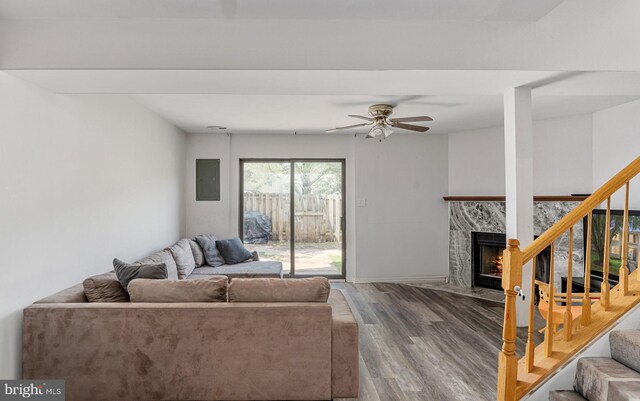 living room with wood finished floors, a high end fireplace, stairs, and ceiling fan