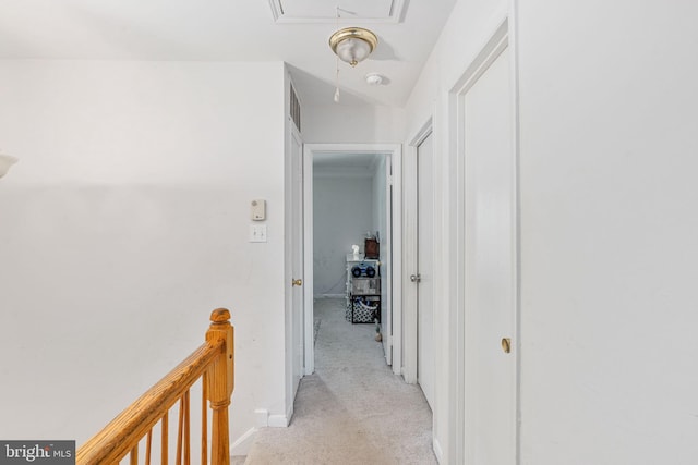 corridor with attic access, an upstairs landing, light colored carpet, and baseboards