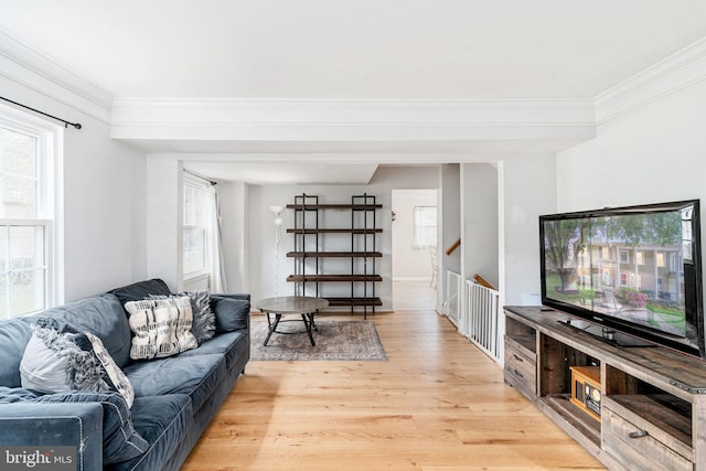 living room featuring light wood-type flooring, plenty of natural light, ornamental molding, and stairs