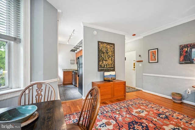 dining space featuring track lighting, baseboards, ornamental molding, and wood finished floors