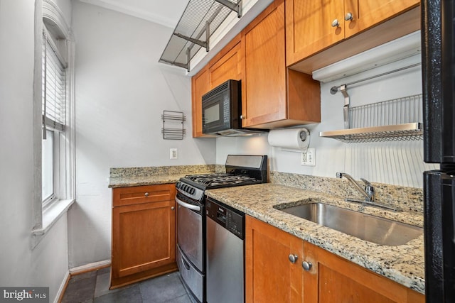 kitchen featuring light stone countertops, a sink, brown cabinetry, stainless steel appliances, and baseboards