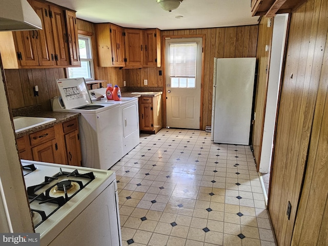 laundry room with laundry area, washer and clothes dryer, light floors, and wooden walls