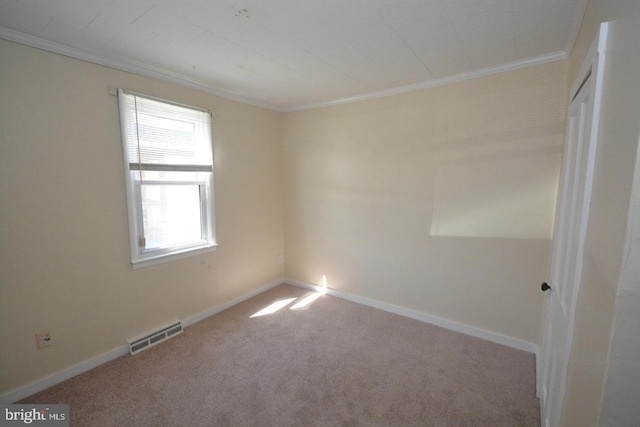 empty room with crown molding, carpet flooring, and visible vents