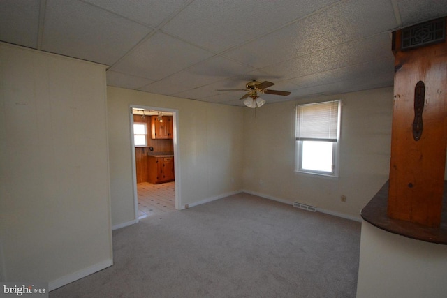 spare room with ceiling fan, visible vents, carpet floors, baseboards, and a drop ceiling