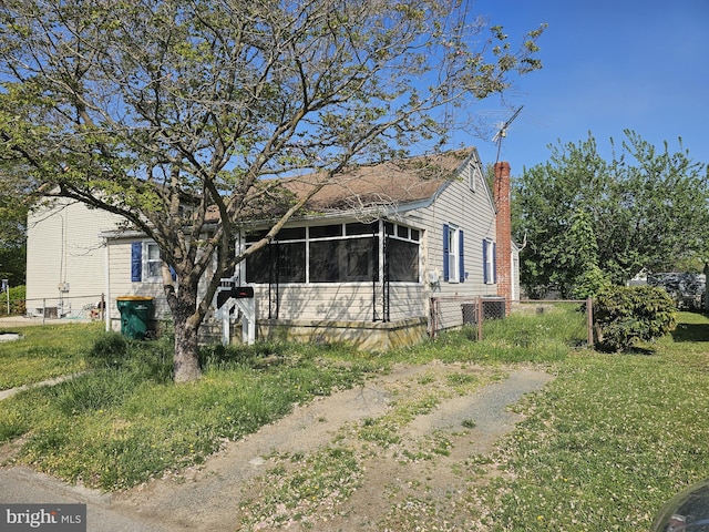 bungalow featuring a sunroom, fence, and a chimney