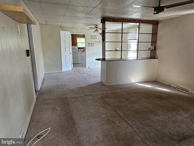 carpeted spare room with separate washer and dryer, ceiling fan, baseboards, and a drop ceiling