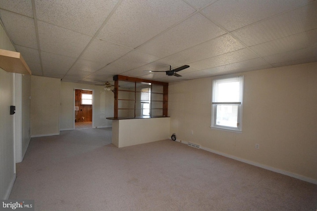 interior space featuring carpet flooring, ceiling fan, visible vents, and a drop ceiling