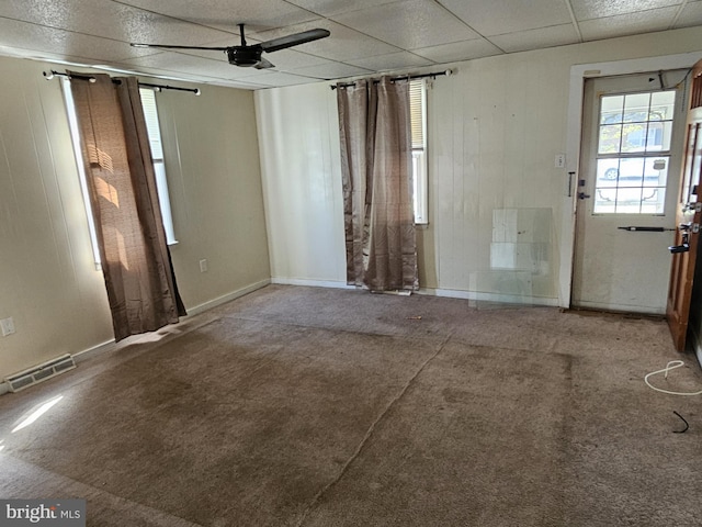 empty room with ceiling fan, visible vents, carpet floors, baseboards, and a drop ceiling