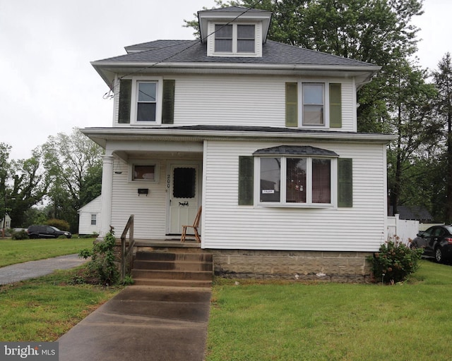 american foursquare style home featuring a front lawn and roof with shingles