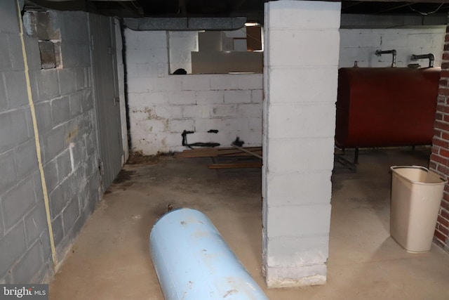 unfinished basement featuring oil tank and concrete block wall
