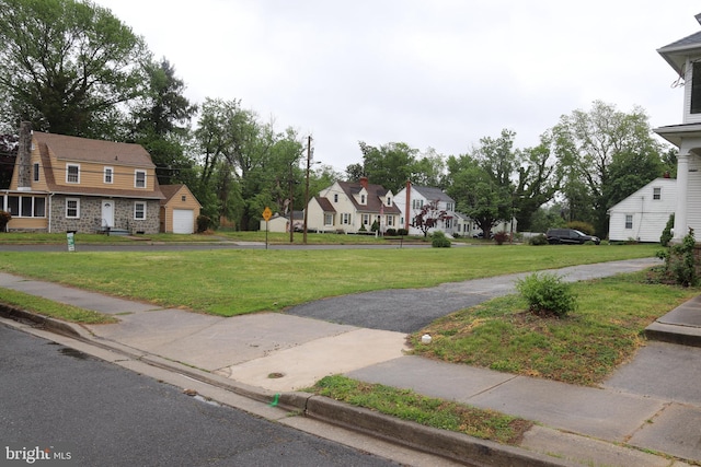 view of green lawn featuring a residential view and a detached garage