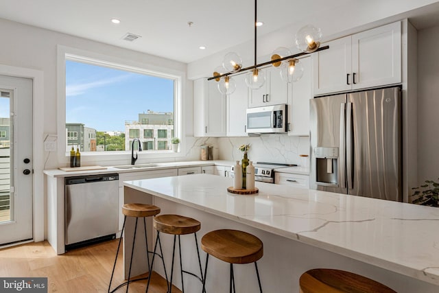 kitchen featuring visible vents, light stone countertops, white cabinetry, a sink, and stainless steel appliances