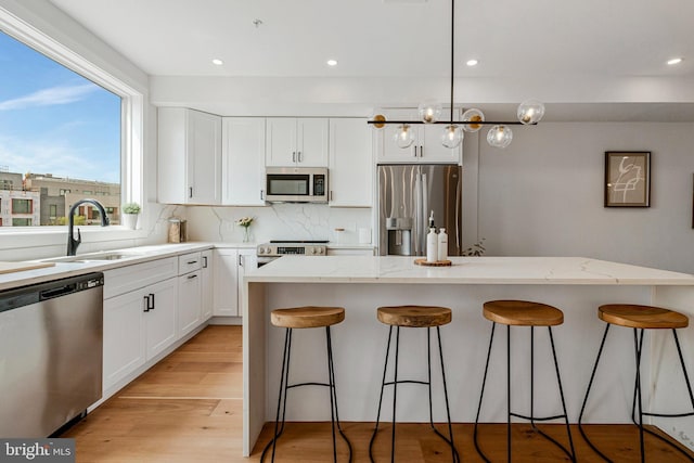 kitchen featuring a sink, a breakfast bar, stainless steel appliances, and white cabinetry