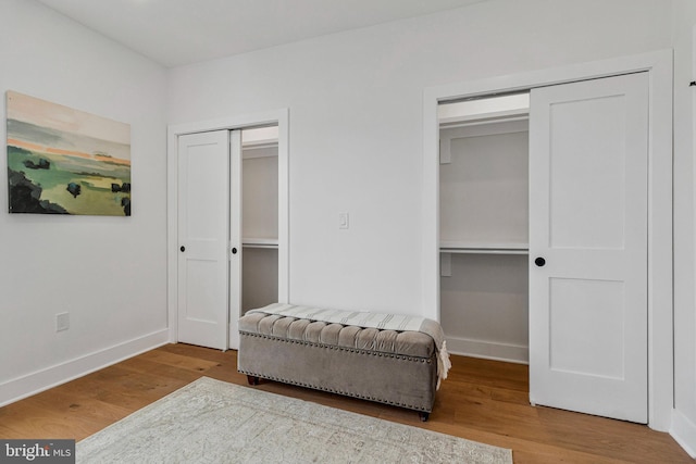 interior space featuring baseboards, multiple closets, and wood finished floors