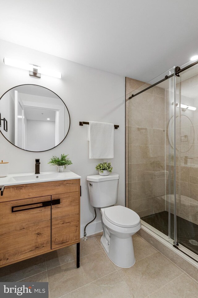 full bath featuring tile patterned flooring, vanity, toilet, baseboards, and a stall shower