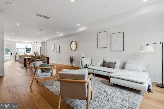 living room featuring baseboards, visible vents, and light wood-style flooring
