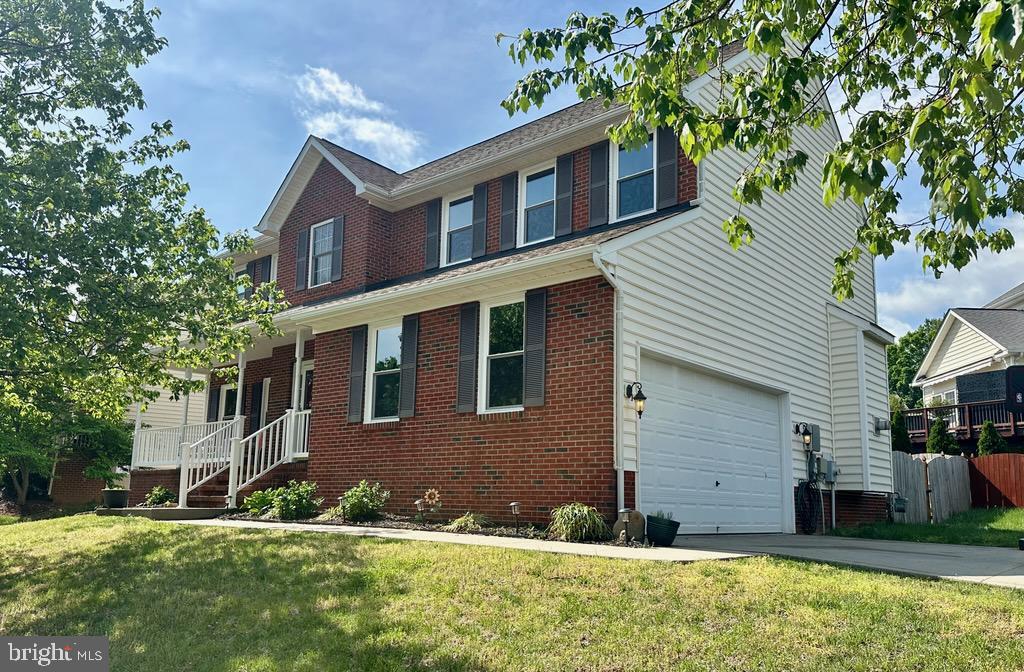 view of front of property with fence, a front yard, brick siding, concrete driveway, and an attached garage