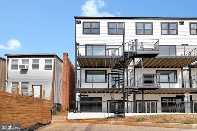 view of front of home featuring fence, a balcony, and cooling unit