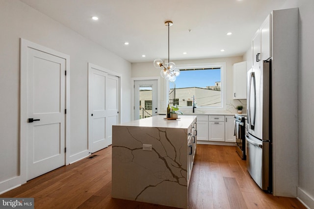 kitchen featuring a kitchen island, stainless steel appliances, light wood-type flooring, and white cabinets