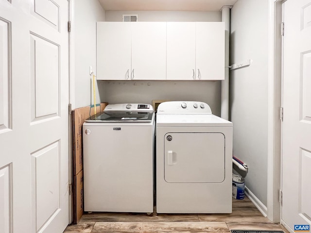 washroom featuring washing machine and dryer, light wood-type flooring, cabinet space, and visible vents