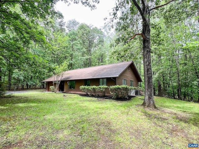 view of front facade with a forest view, cooling unit, and a front yard