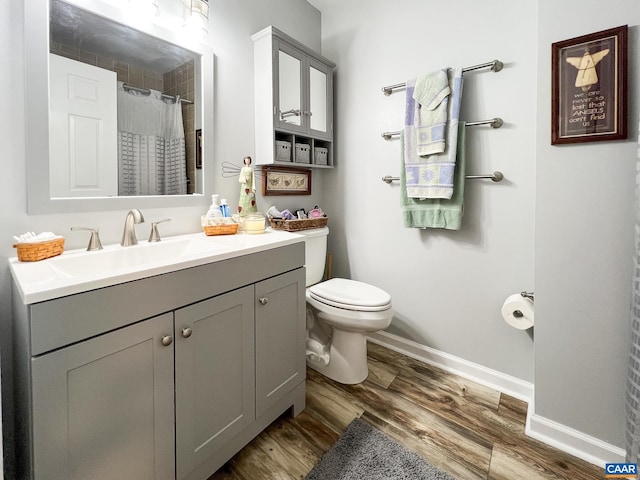 bathroom with vanity, wood finished floors, toilet, baseboards, and a shower with curtain